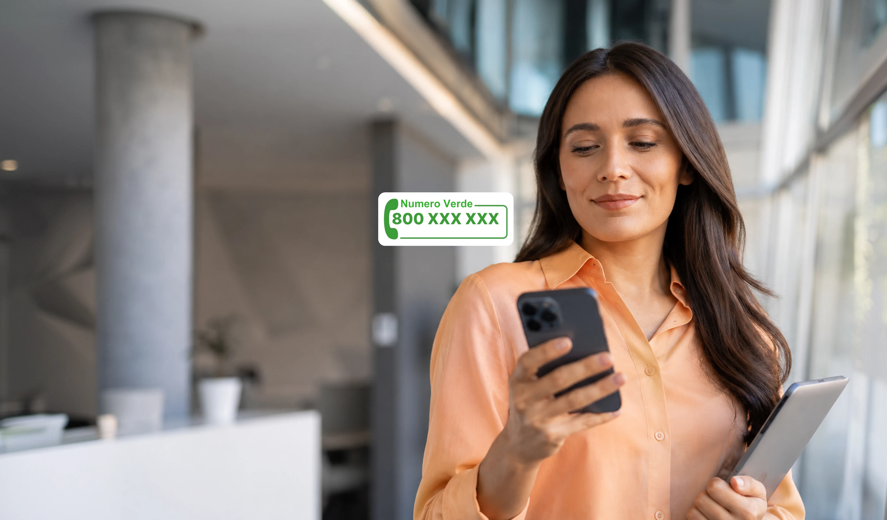 Numero Verde aziendale MyCentralino — una professionista con lo smartphone in mano accanto alla targhetta di un numero verde 800