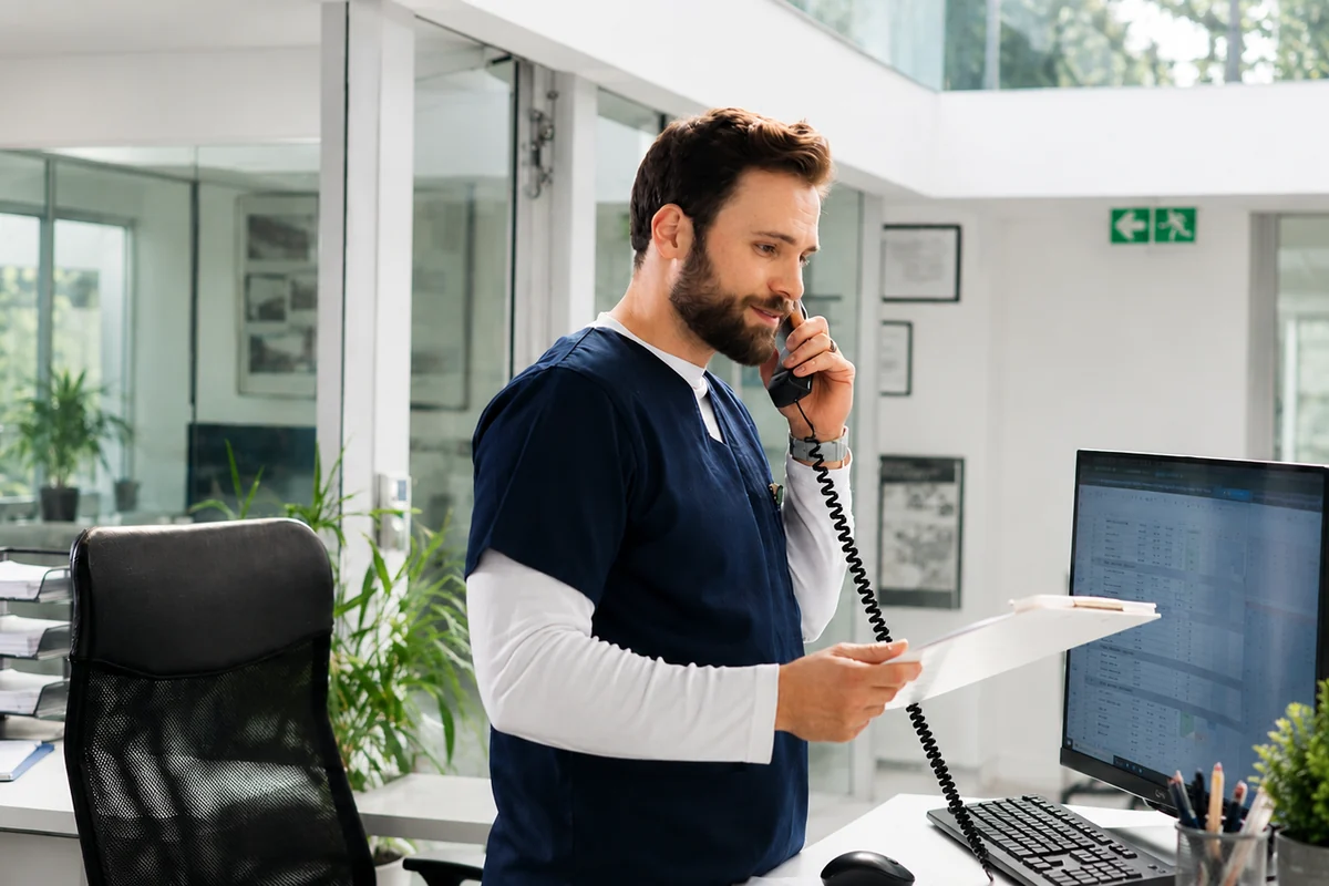 Addetto alla segreteria di uno studio medico risponde al telefono alla reception